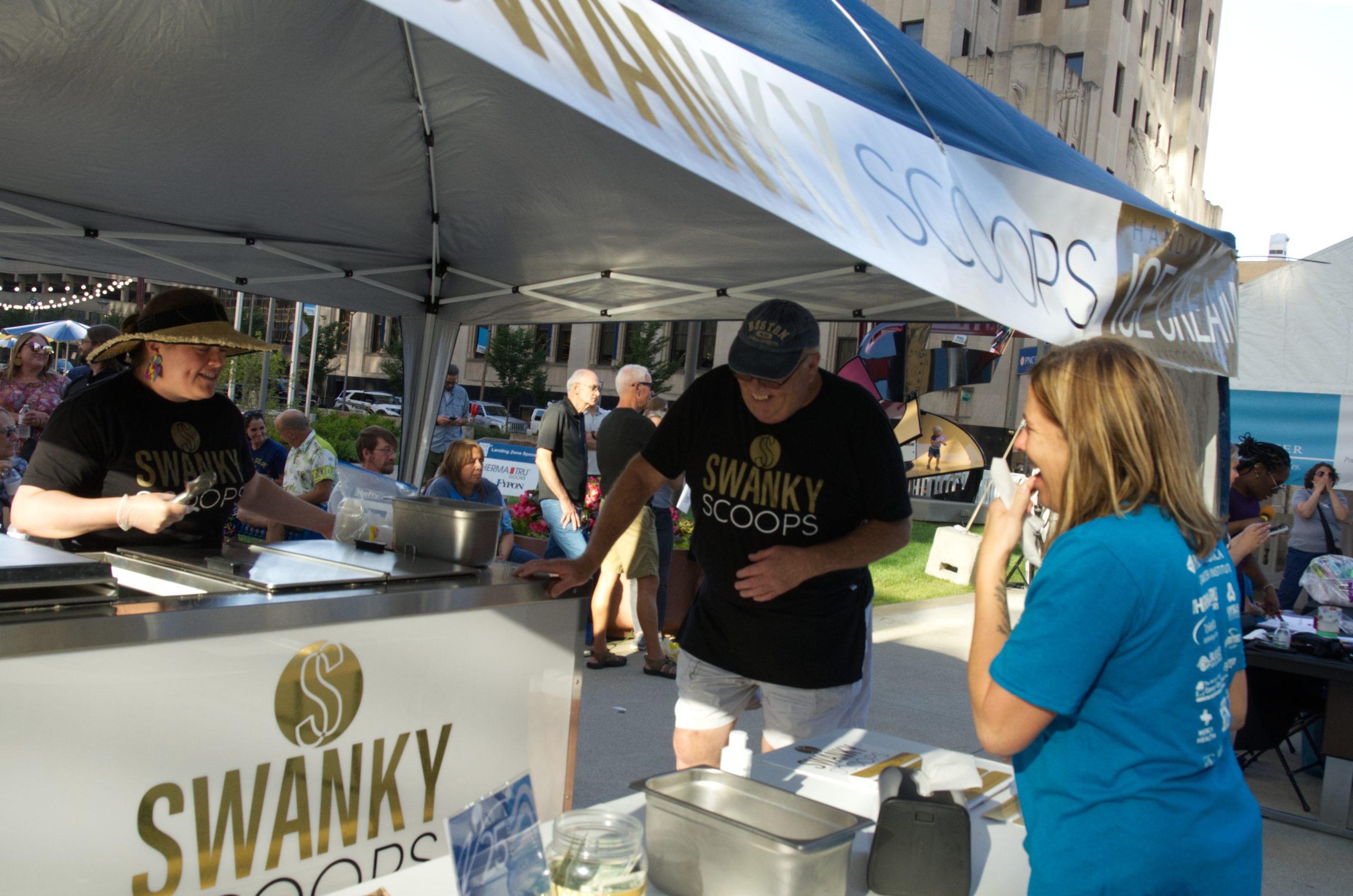 Swanky Scoops stand at an outdoor event, three people interacting.