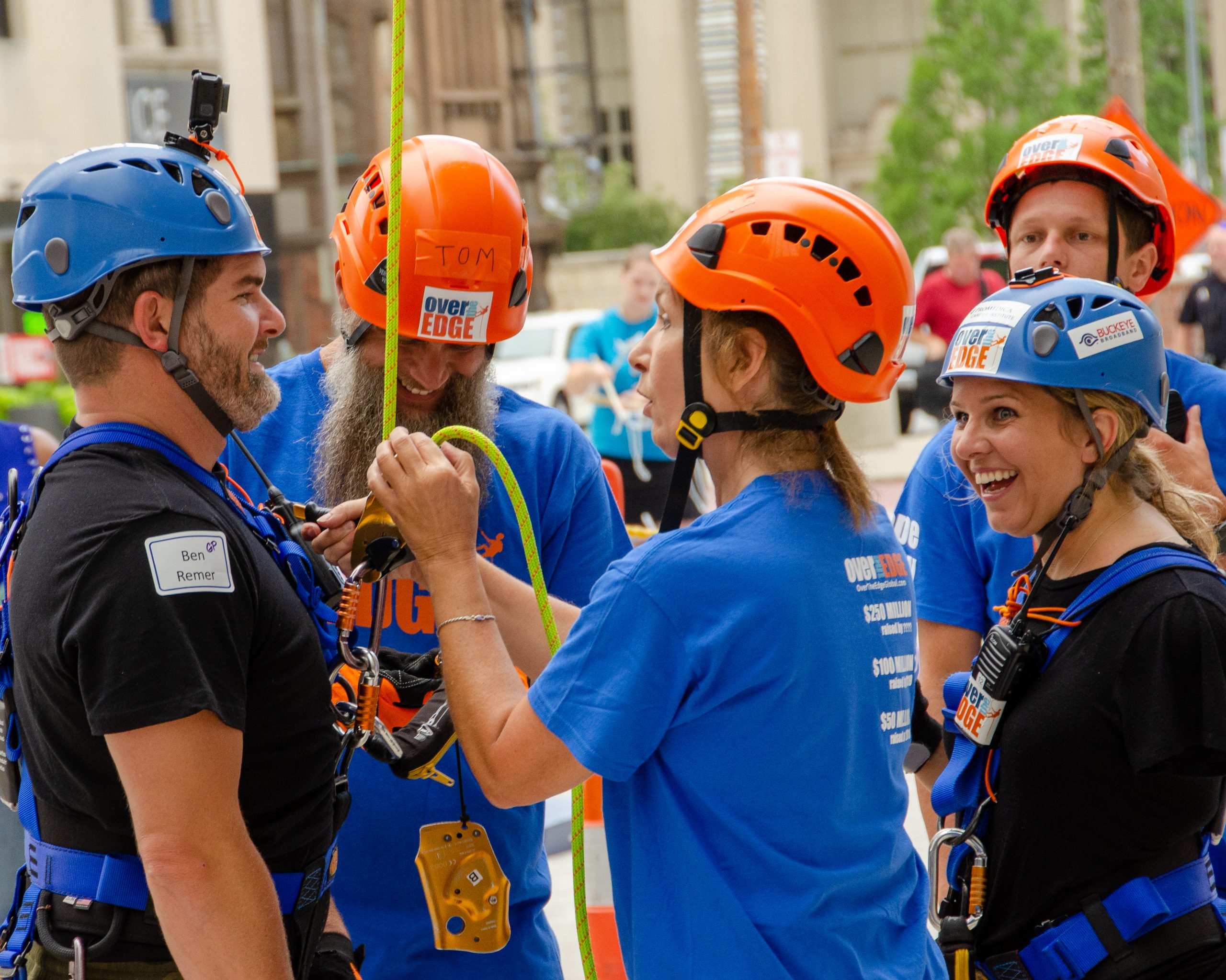 Group of people in helmets and harnesses, smiling outdoors.