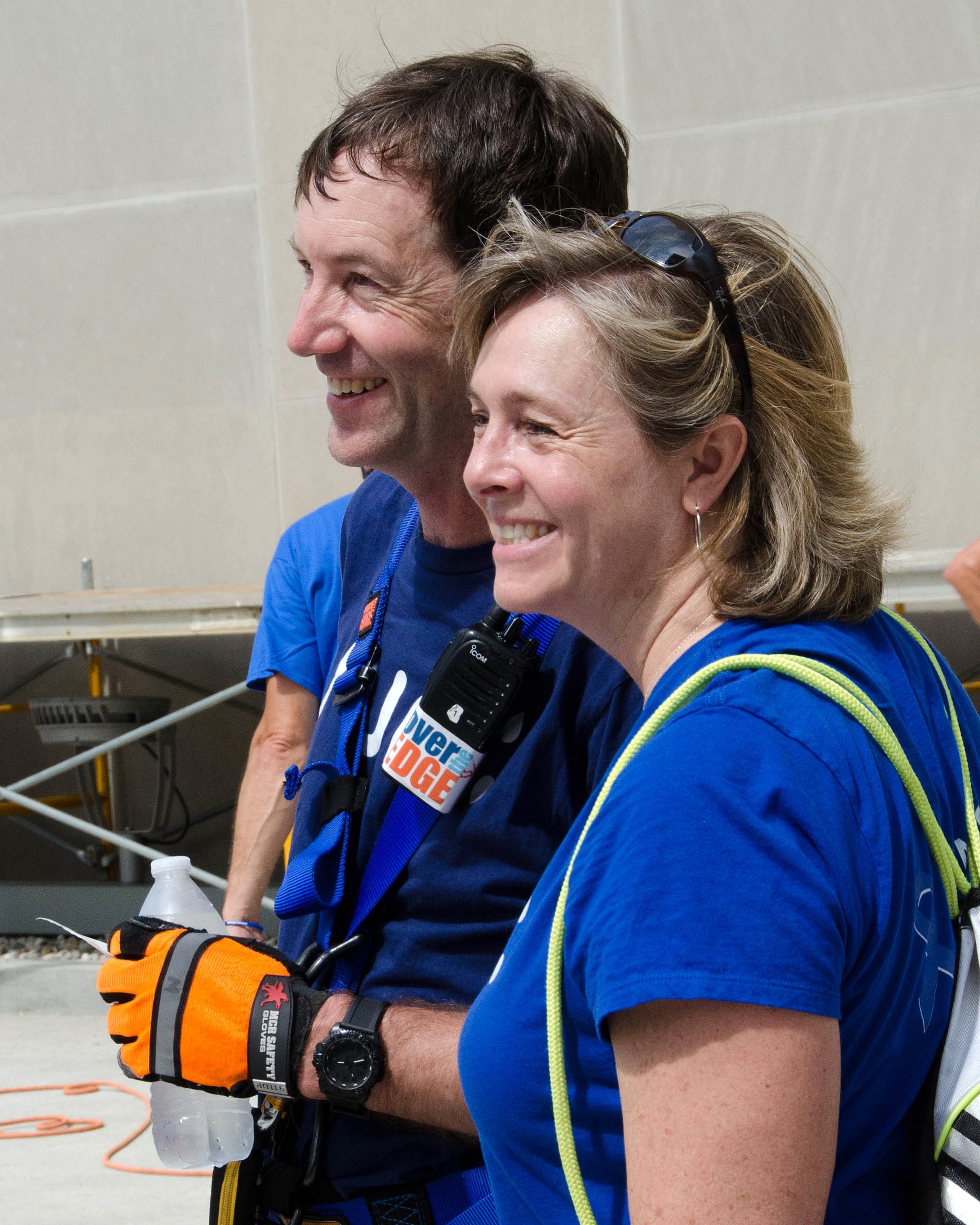 Man and woman smiling on a boat deck, wearing blue shirts.