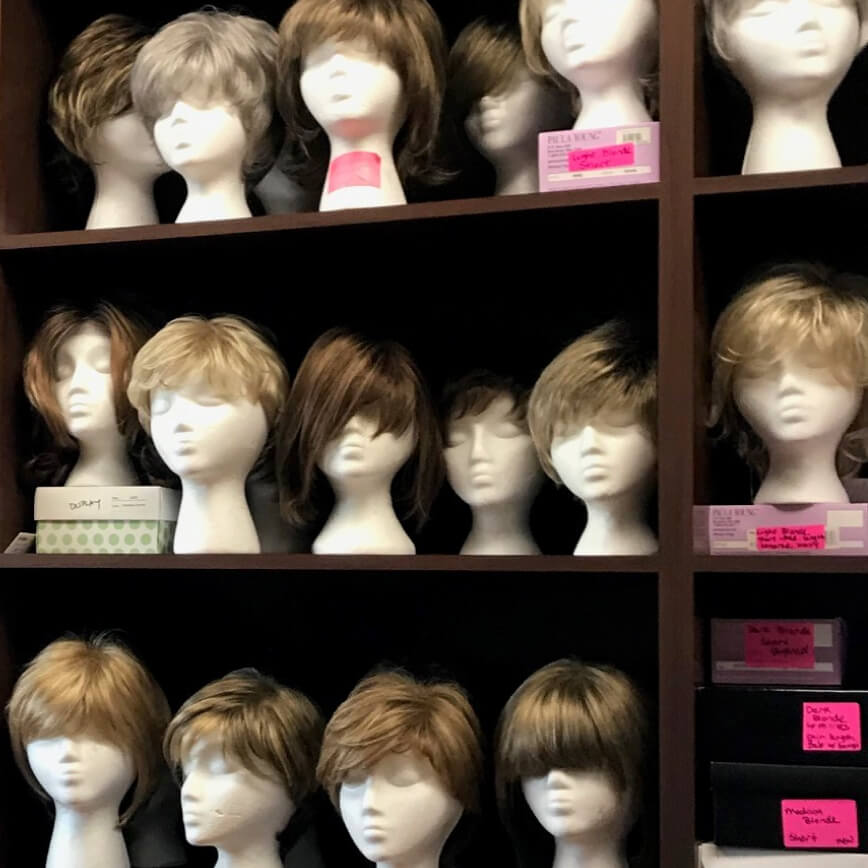 A row of wigs on mannequins