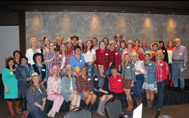 Group of people in casual and western attire smiling at a gathering.