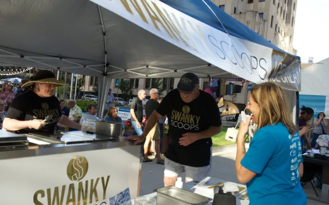 Swanky Scoops stand at an outdoor event, three people interacting.