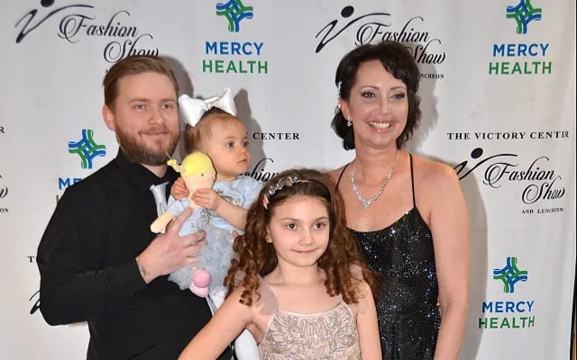 Family posing at an event; two adults and two children in formal attire.