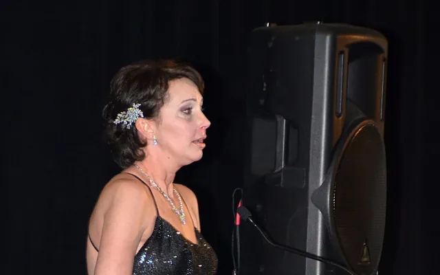 Woman in a black dress speaking at a podium.