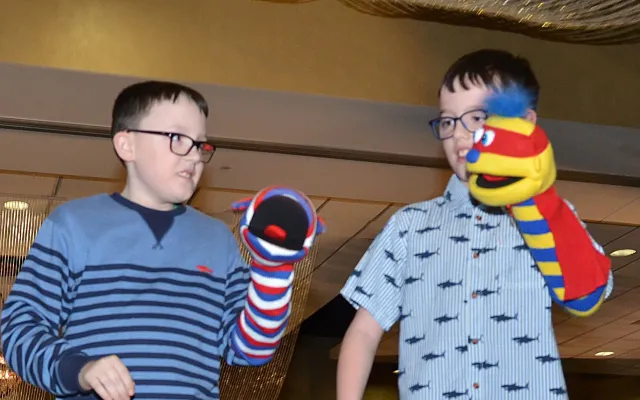 Two children with sock puppets perform on stage.