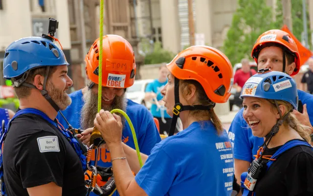 Group of people in helmets and harnesses, smiling outdoors.