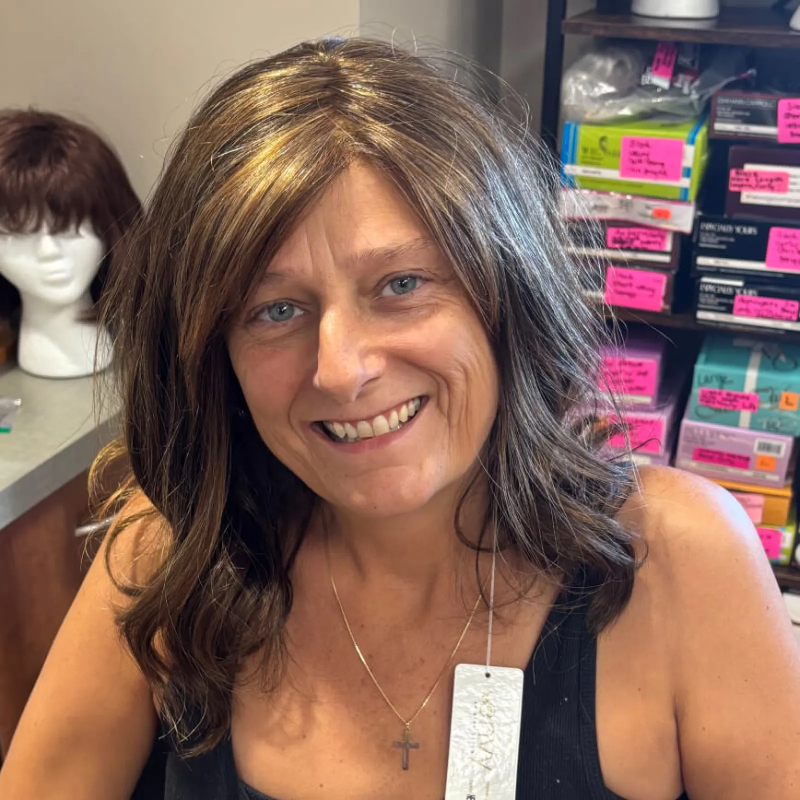 Smiling woman wearing a wig in a colorful setting.