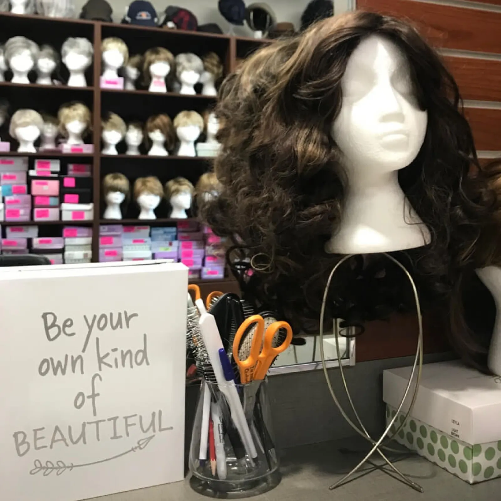 Wig display on mannequin head with supplies on counter.